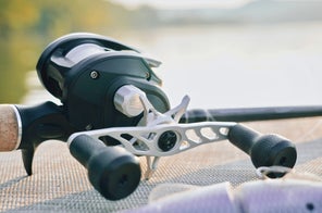 A Bates Goat SWM 200 reel sitting next to a lake.