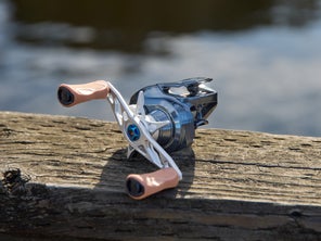 Display of the bates fishing co. salty hundo casting reel on top of a wood railing
