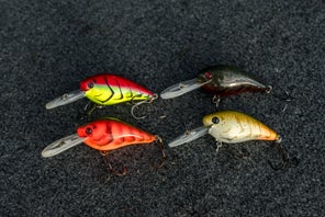 Four Strike King Gravel Dawg crankbaits of different colors laying on a carpeted bass boat deck.