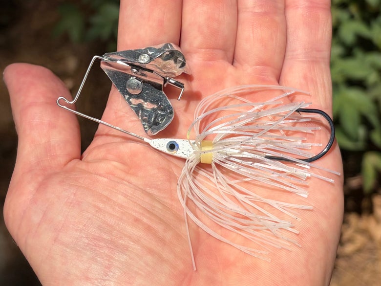 A white 1/8 ounce Strike King Buzz King buzzbait is shown in the palm of a hand.