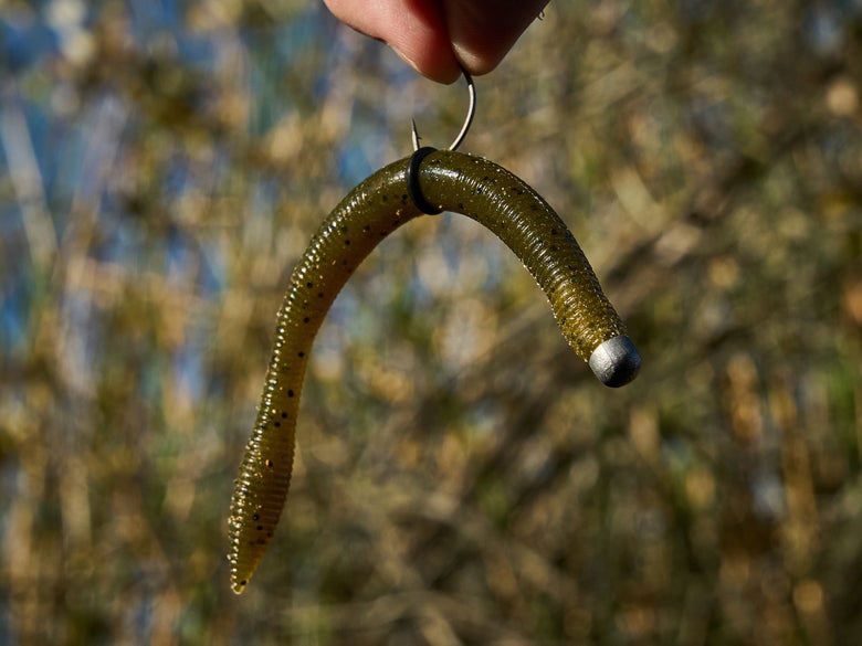 A green pumpkin with black flake Daiwa Yamamoto Neko Fat Worm is shown fully neko rigged with an O-ring.