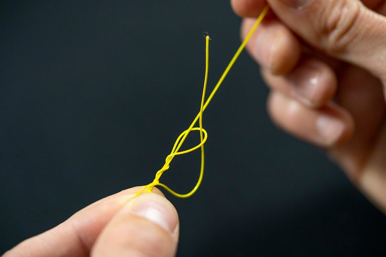 Thread Tag End through Top of Knot