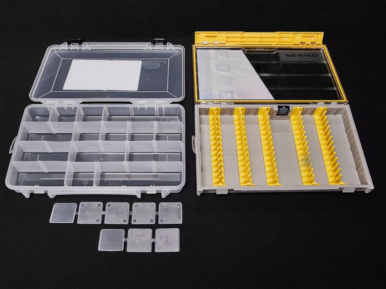 Two empty hardbait boxes with lids open showcasing their interior storage layouts.