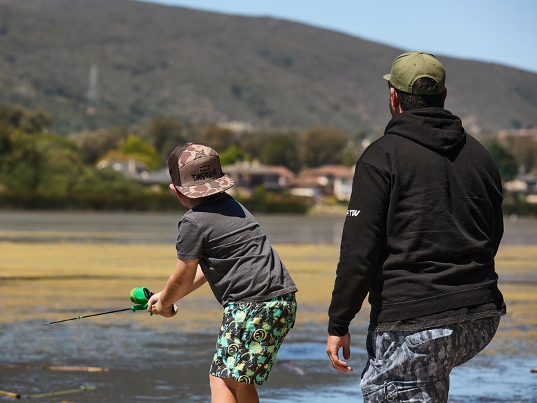 Image of small kid casting push button reel off of dock