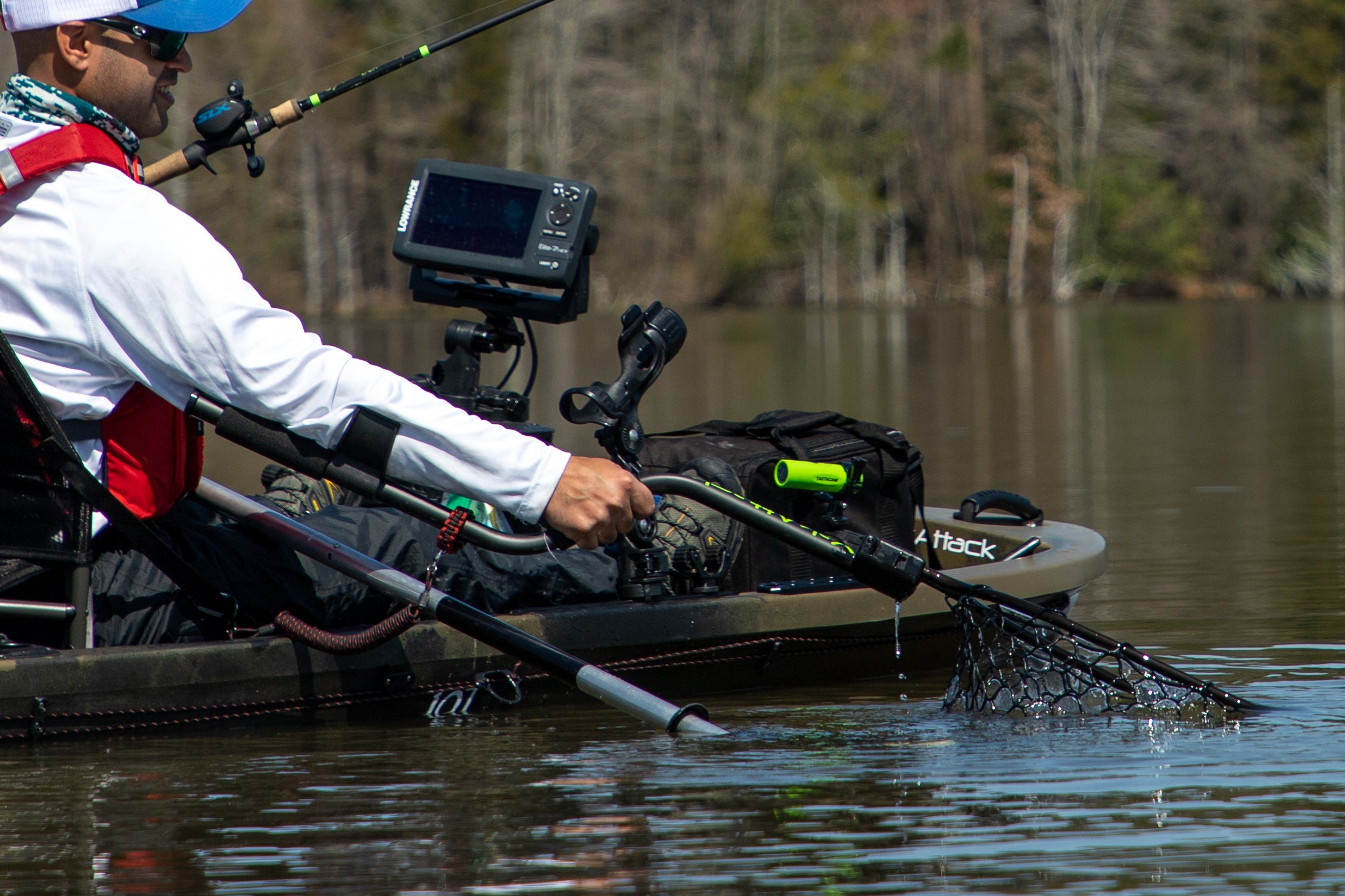 Angler netting a bass from kayak