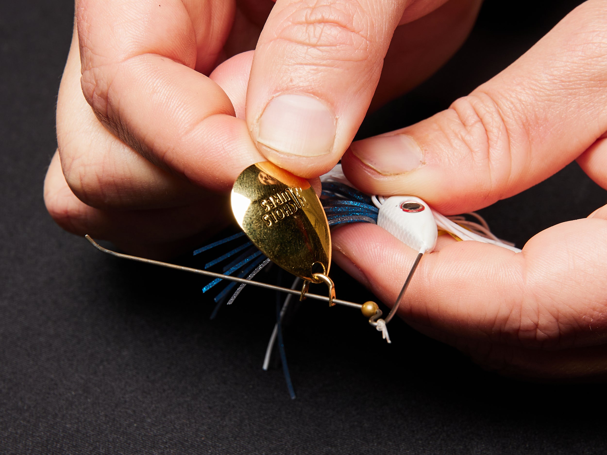 Sliding a new blade onto the wire of a spinnerbait.