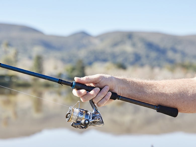 Spinning rod and reel with a lake and mountains in the background